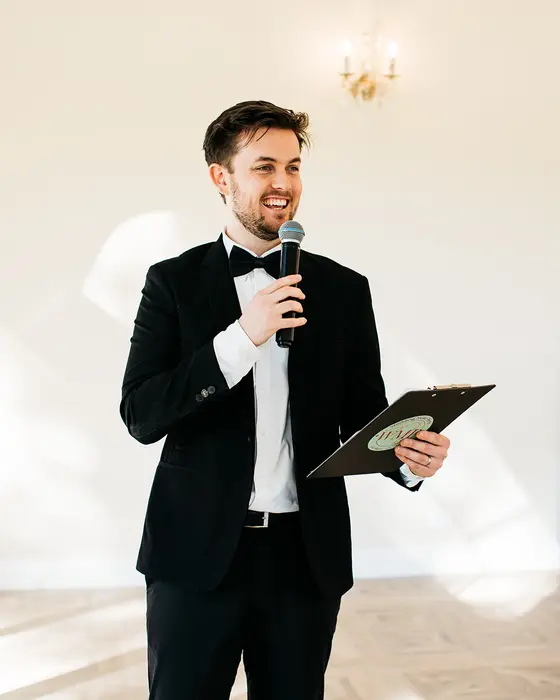 Mitchell MCing with a microphone and runsheet